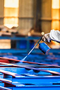 Paint workshop worker in protective suit spraying painted frames