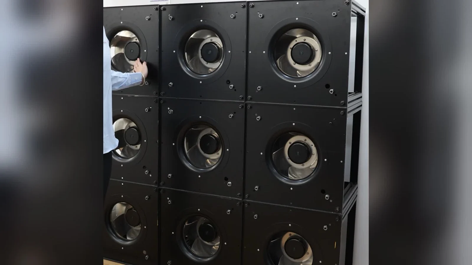 Visible nine-module fan array with a technician beside the frame