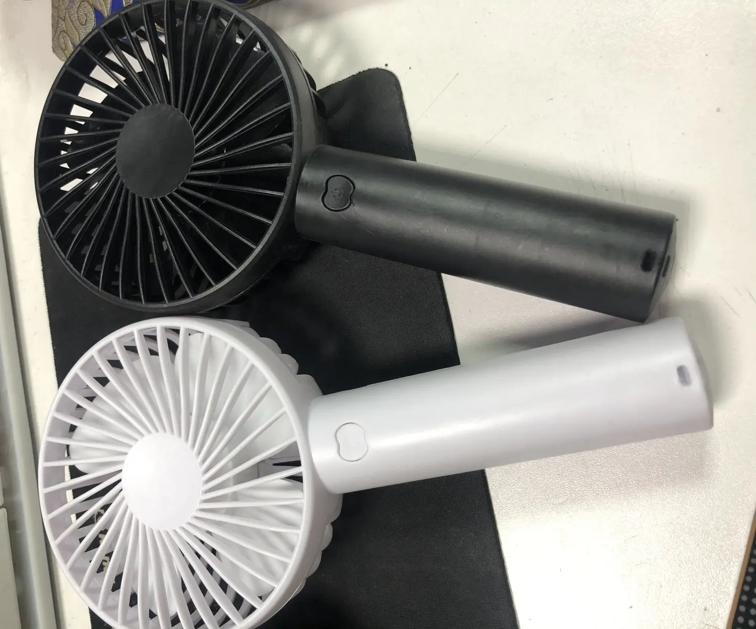 Two handheld rechargeable fans, one black and one white, as custom colour samples