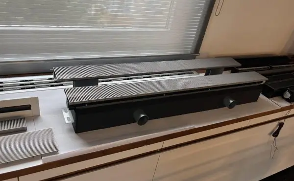 Two cross-flow fan assemblies laid out beside a finished convector on the customer s bench, with spare grille secti