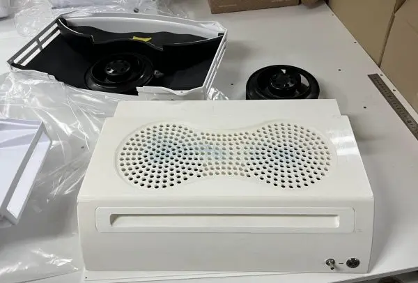 A pair of double-inlet centrifugal blowers next to the moulded housing they go into, still in their packaging