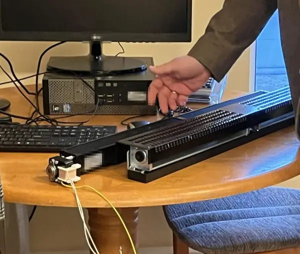 Two slim finned convector elements set up on an office desk for a powered bench check: a small fan drive motor with
