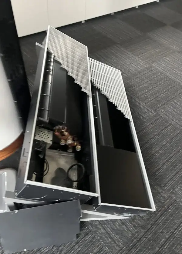 A customer's fan-assisted trench convector opened up during our 2023 visit: the linear grilles have been lifted off