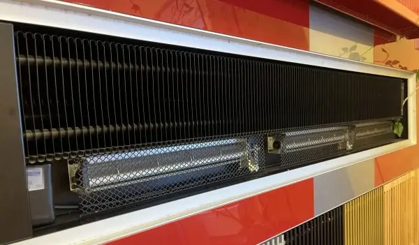 Cut-away view inside a wall-mounted convector: a finned heat-exchanger coil above, and beneath it two tangential (c