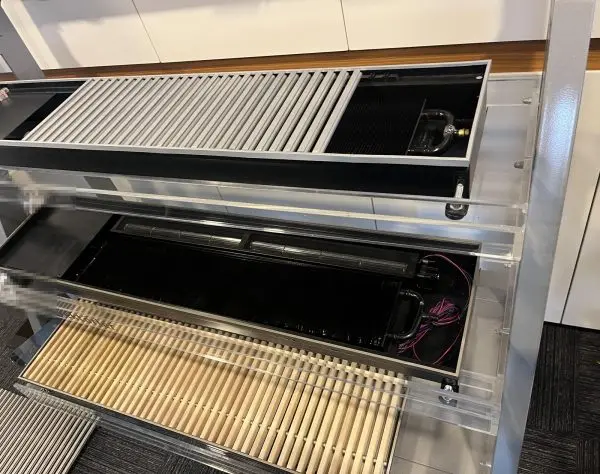 Cut-away display units at a customer showroom: a fan-assisted trench (floor) convector opened up to show two tangen