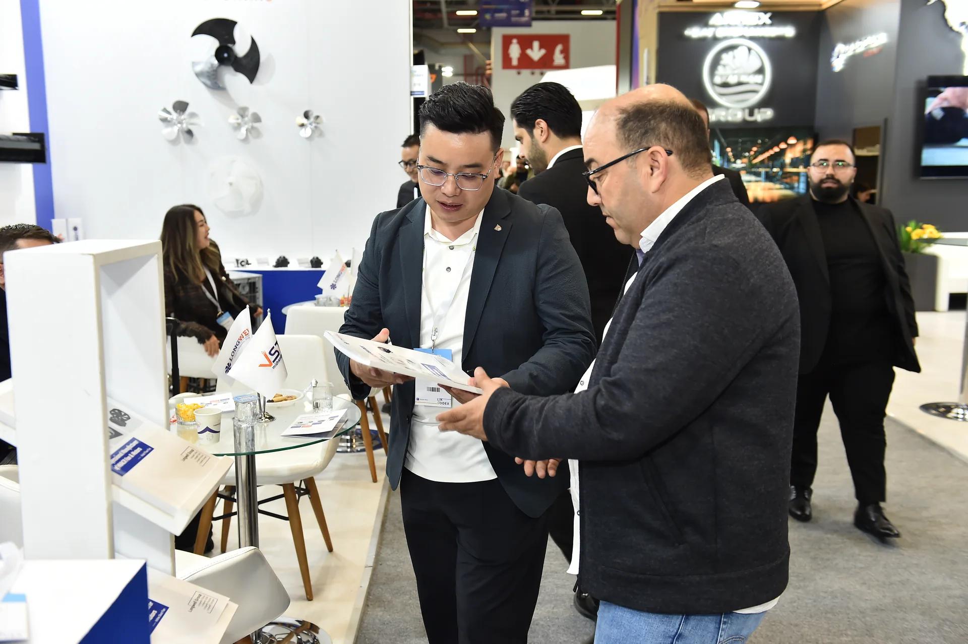 A visitor and LONGWELL team member discuss a displayed fan at ISK-SODEX 2025.