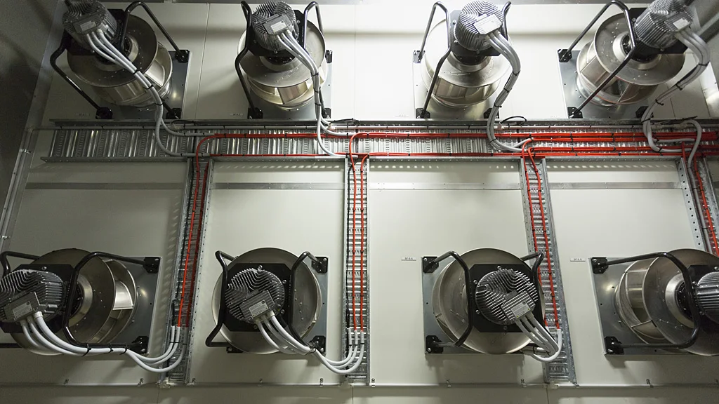 Multiple centrifugal fan modules arranged in a wall with visible cable routing